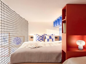 A bedroom with a bed, a reading area with a magazine, a bookshelf, and a decorative wall. - TurnKey | Vinohrady Modern Loft Apartment II (Prague 3)