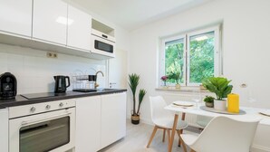 A modern kitchen with white cabinets, a built-in oven, and a dining area with a table and chairs.
