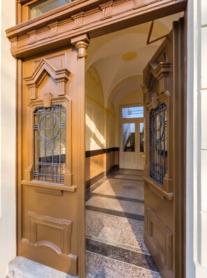 A hallway with a double door, a staircase, and a patterned floor. - TurnKey | Vinohrady Modern 2BR Ap. with Balcony (Prague 3)