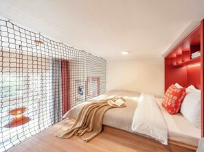 A bedroom with a bed, a red headboard, a knitted blanket, and a window with a view. - TurnKey | Vinohrady Modern 2BR Ap. with Balcony (Prague 3)