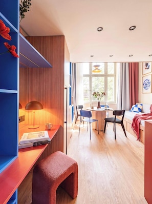 A modern room with a wooden desk, a reading chair, a sofa, and a dining area. - TurnKey | Vinohrady Modern 2BR Ap. with Balcony (Prague 3)