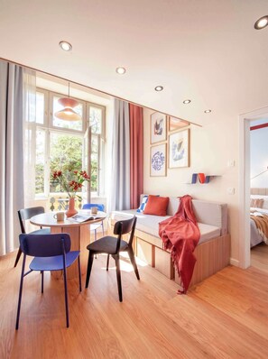 A modern living room with a sofa, chairs, a dining table, and artwork on the walls. - TurnKey | Vinohrady Modern 2BR Ap. with Balcony (Prague 3)