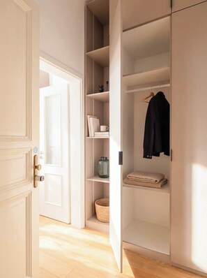Un dressing avec des portes ouvertes, des étagères et un espace pour suspendre les vêtements.
