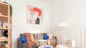 Ein modernes Wohnzimmer mit einem grauen Sofa, einem weißen Sessel, einem runden Couchtisch und einem Bücherregal.