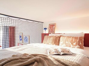A hotel room with a bed, a netted window, a lamp, and a framed picture on the wall.