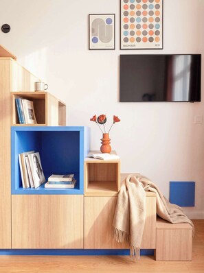 A modern living room with a built-in bookshelf, a flat-screen TV, and a cozy seating area with a blanket.