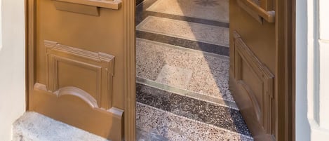 Un pasillo con una puerta doble, una escalera y un suelo estampado.