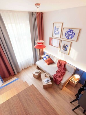 A modern bedroom with a bed, bedside tables, a hanging lamp, and artwork on the wall.