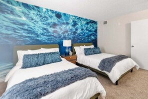 Ein Hotelzimmer mit zwei Betten, einem großen Wandbild und einem Nachttisch mit Lampe.