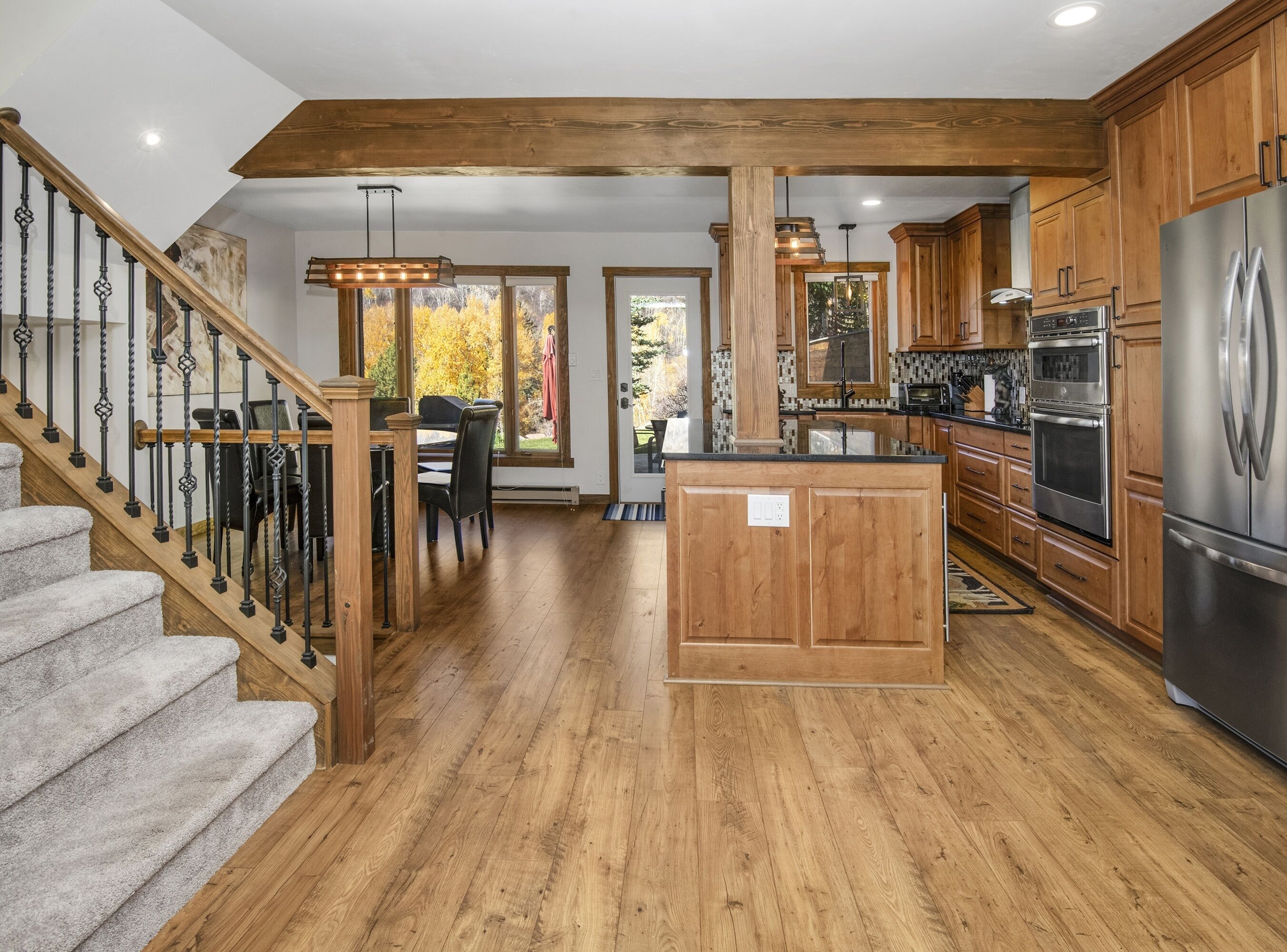 A spacious kitchen with wooden cabinets, a stainless steel refrigerator, and a wooden island.