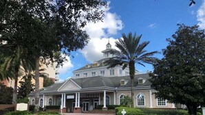 A large, historic building with a central entrance, surrounded by well-maintained landscaping and palm trees. - Sunset Games Retreat At Reunion Resort 6 Bedroom Villa (Kissimmee)