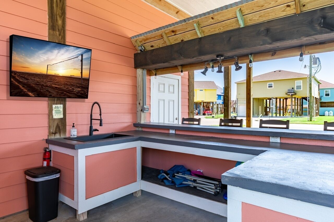 A kitchenette with a sink, a trash can, and a window overlooking a playground.