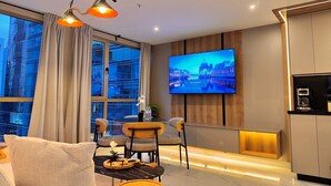 Una sala de estar moderna con un televisor grande, asientos cómodos y una zona de cocina.