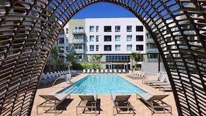 A pool area with lounge chairs and a view of a multi-story building.