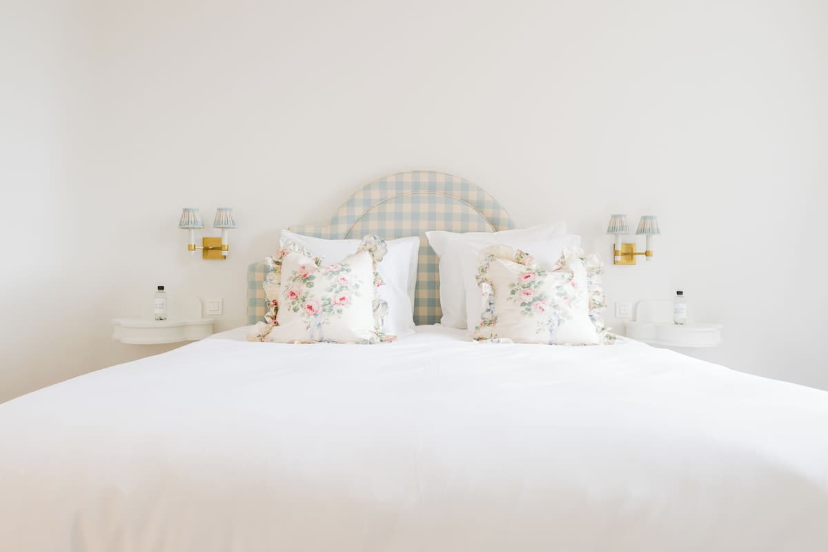 A neatly made bed with floral pillows and a checkered headboard.