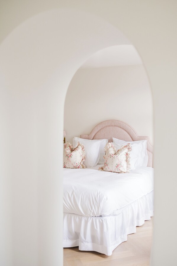 A bedroom with a white bed, pink headboard, and floral pillows. - La Villa Rosa (Bruges)