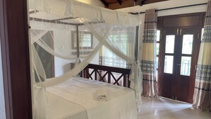 Un dormitorio con cama con dosel, cabecera de madera y un banco de madera.