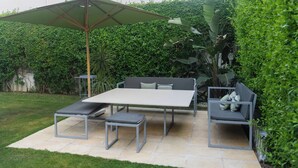 A patio with a table and chairs, surrounded by a hedge.