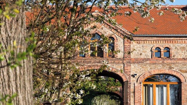 Un bâtiment historique doté d’une entrée en arc de cercle, de murs en briques et d’une porte en bois.