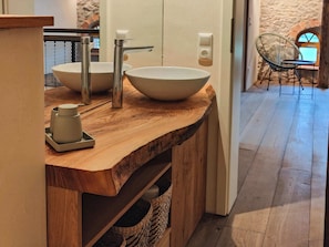 A wooden vanity with two vessel sinks, a small cabinet, and a chair in the background. - Private sauna, 2 fireplaces: Bright 3-bedroom flat (Großharthau)