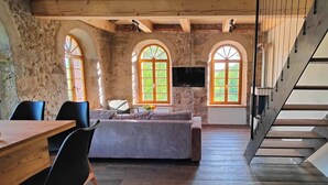 A rustic room with a wooden table, chairs, a sofa, a TV, and arched windows. - Private sauna, 2 fireplaces: Bright flat - last minute (Großharthau)