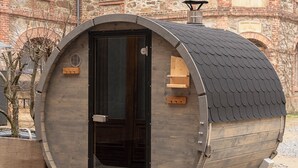 A cylindrical wooden structure with a door, a small window, and a chimney. - Two-storey accommodation with terrace and fireplace – last minute (Großharthau)