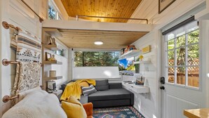 A cozy interior with a sofa, patterned rugs, and a wooden ceiling.