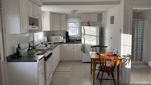 A compact kitchen with white cabinets, a microwave, a stove, and a dining area with a wooden table and chairs.