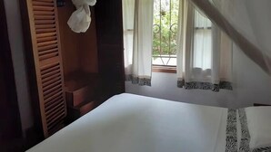 Un dormitorio con cama con dosel, armario de madera y ventana con cortinas.