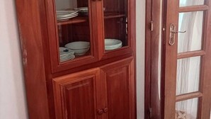 Un armario de madera con puertas de cristal, que contiene platos y cuencos apilados.