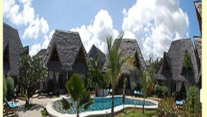 Un resort con cabañas de techo de paja, una piscina y sillas de descanso.