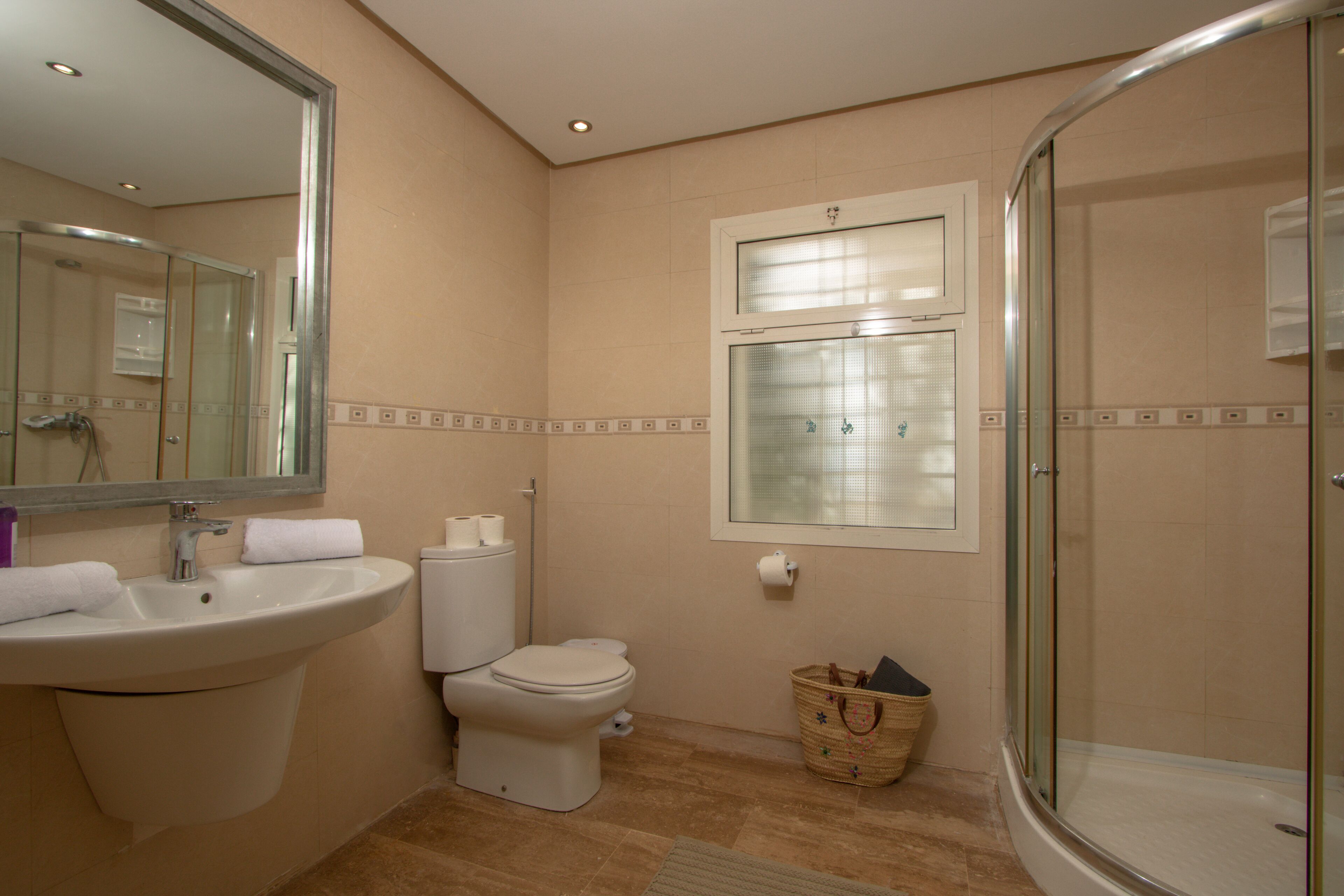 Un baño con lavamanos, inodoro y cabina de ducha de vidrio.