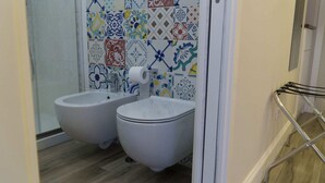 Ein Badezimmer mit zwei Bidets, einer Toilette und einer Duschkabine.
