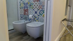 Un baño con dos bidés, un inodoro y una zona de ducha.