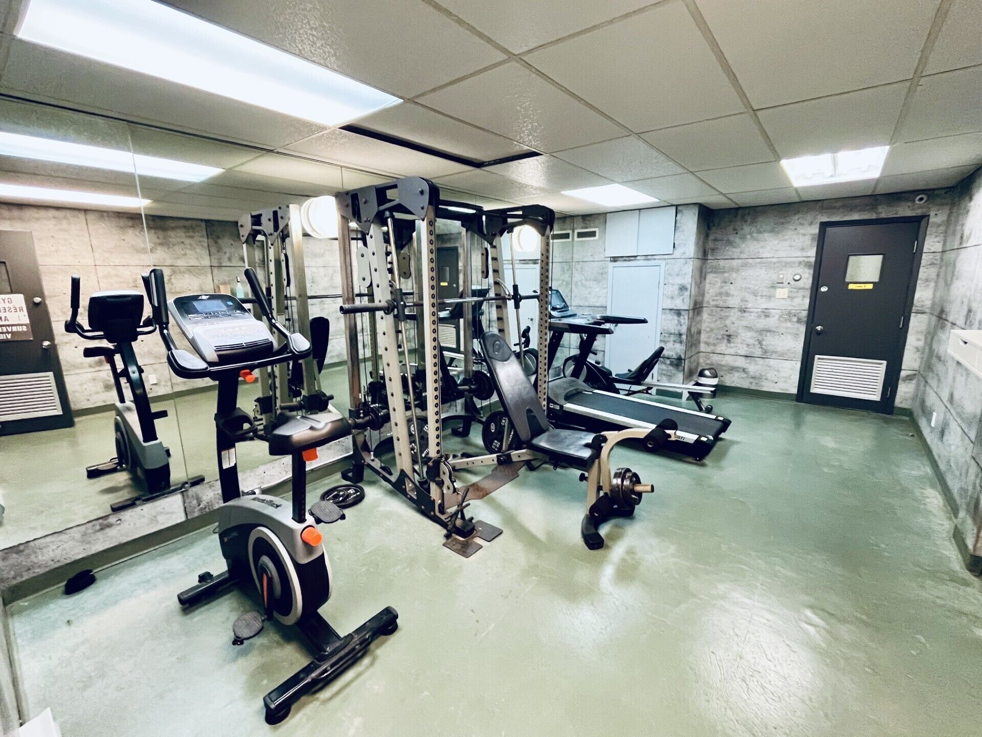 A gym with various exercise equipment, including treadmills, weight machines, and a stationary bike.