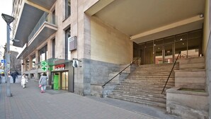 A building with a staircase leading to an entrance, a green sign with a plus symbol, and a sign indicating a pharmacy. - North Ave. apartment by Luxe Group HH777 (Yerevan)