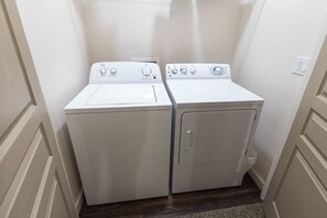 A laundry room with two front-loading washing machines and a dryer.