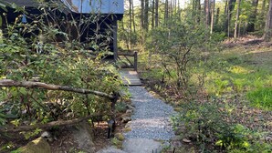 A wooden pathway leading to a rustic cabin surrounded by dense forest. - Rustic Log Cabin- In Town Cashiers- Pet-Friendly! (Cashiers)