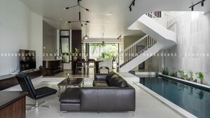 A modern living room with a pool, a staircase, and a dining area.