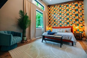 Un dormitorio con cama, sofá, mesa de centro, planta en maceta y pared con diseño.
