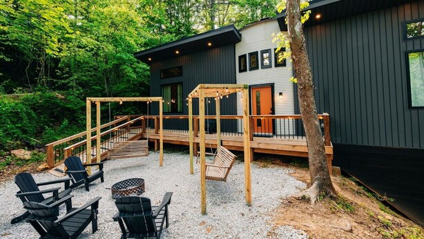 Uma cabana com varanda, mobiliário de exterior e um espaço com brita.