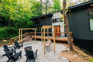 A cabin with a deck, outdoor seating, and a gravel area.