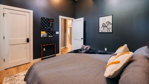 Um quarto com uma cama, uma porta, um espelho e um quadro emoldurado na parede.
