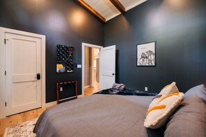 A bedroom with a bed, a door, a mirror, and a framed picture on the wall. - Hot Tub + SxS Trails | Vibrant Silo Cabin | Kings (Beattyville)