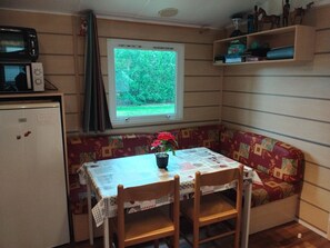 Eine kleine Küche mit Mikrowelle, Kühlschrank und einem Fenster mit Blick ins Grüne.