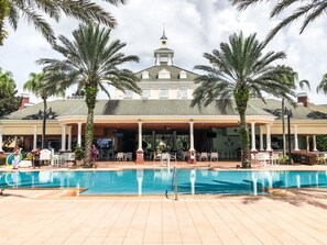 Un hotel con piscina, palme e posti a sedere all'aperto.