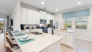 A modern kitchen with white cabinets, stainless steel appliances, and a large island with seating.