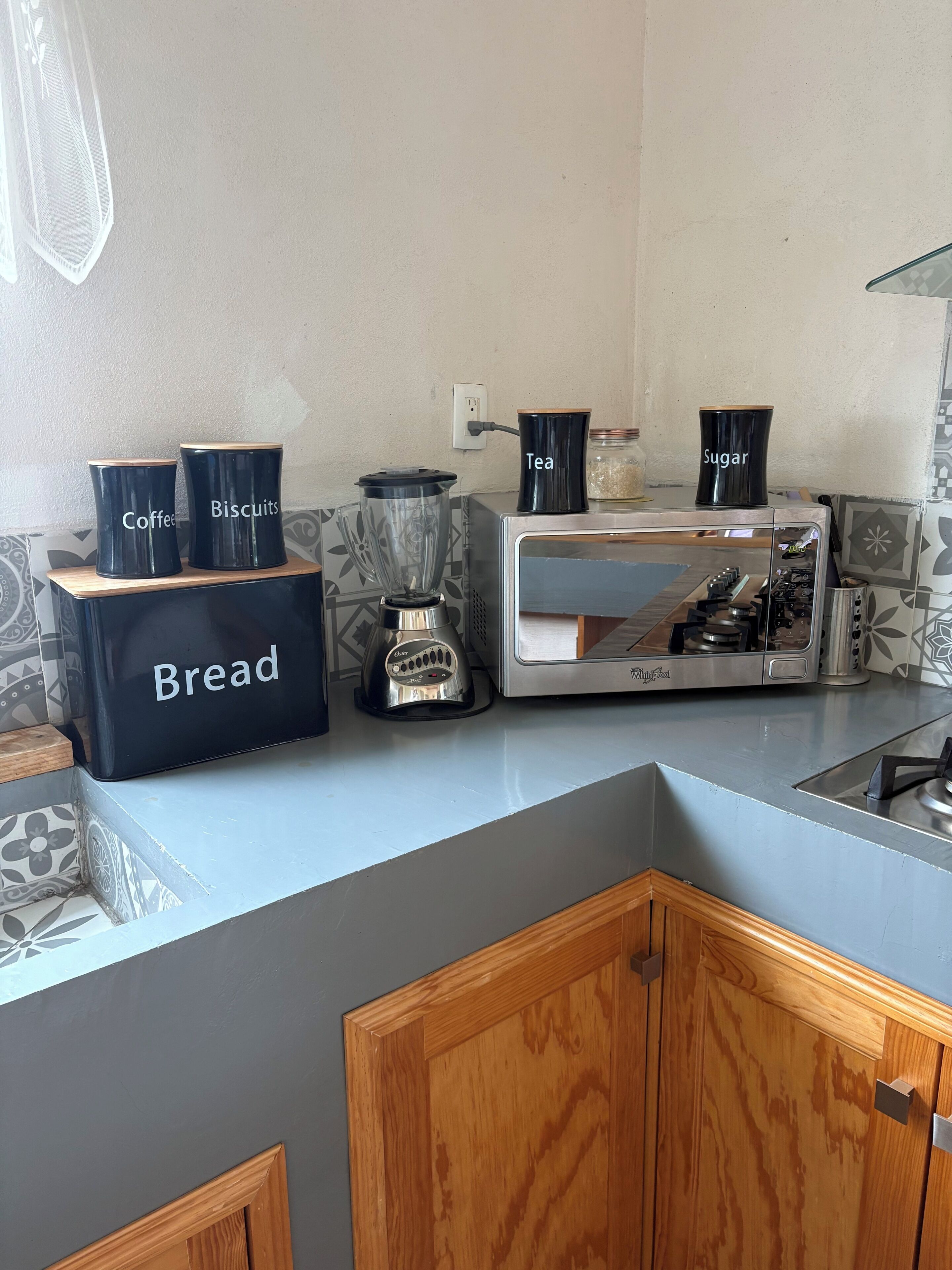 A kitchen with a bread box, a coffee maker, and a toaster.