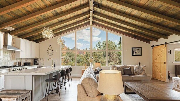 Una cocina amplia con una isla grande, taburetes de bar, un sofá y una mesa de comedor.