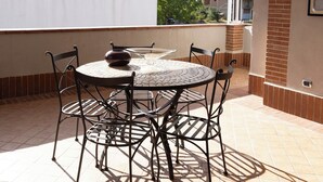 Un patio techado al aire libre con una mesa redonda y cuatro sillas, una campana colgante y vistas del entorno.